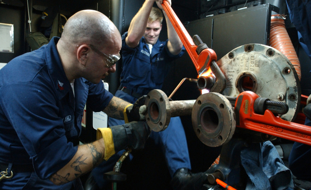 050114-N-8148A-646
Pacific Ocean (Jan. 14, 2005) - Hull Maintenance Technician 1st Class Chip Land, of Boulder, Colo., left, heats-up a nut on a steam coil with a blow torch while Hull Maintenance Technician 3rd Class Jason Roosien, of Grand Rapids, Mich., attempts to break free the nut with a 24" pipe wrench aboard USS Ronald Reagan (CVN 76). The Nimitz-class aircraft carrier Ronald Reagan is underway in the Pacific Ocean conducting routine carrier operations. U.S. Navy photo by Photographer's Mate 3rd Class Kitt Amaritnant (RELEASED)